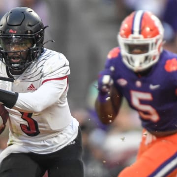 Nov 12, 2022; Clemson, South Carolina, USA; Louisville quarterback Malik Cunningham (3) runs by Clemson defensive end K.J. Henry (5)  during the second quarter at Memorial Stadium in Clemson, South Carolina Saturday, Nov. 12, 2022.