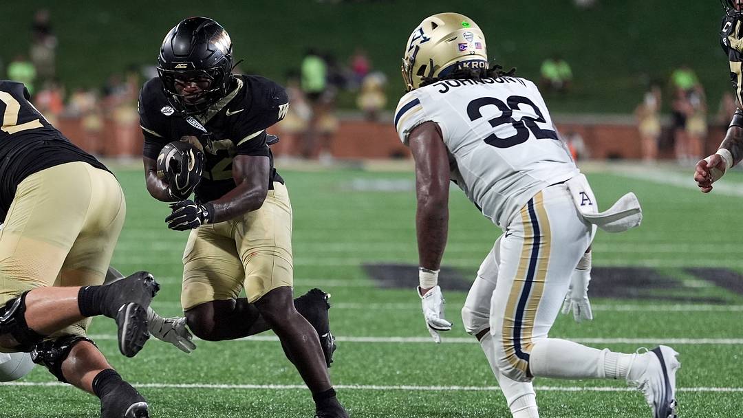 Sep 3, 2026; Winston-Salem, North Carolina, USA;  Wake Forest Demon Deacons running back Deuce Lawrence (22) runs in the red zone defended by Akron Zips linebacker Donelius Johnson (32) during the second half at Allegacy Federal Credit Union Stadium.  Mandatory Credit: Jim Dedmon-Imagn Images