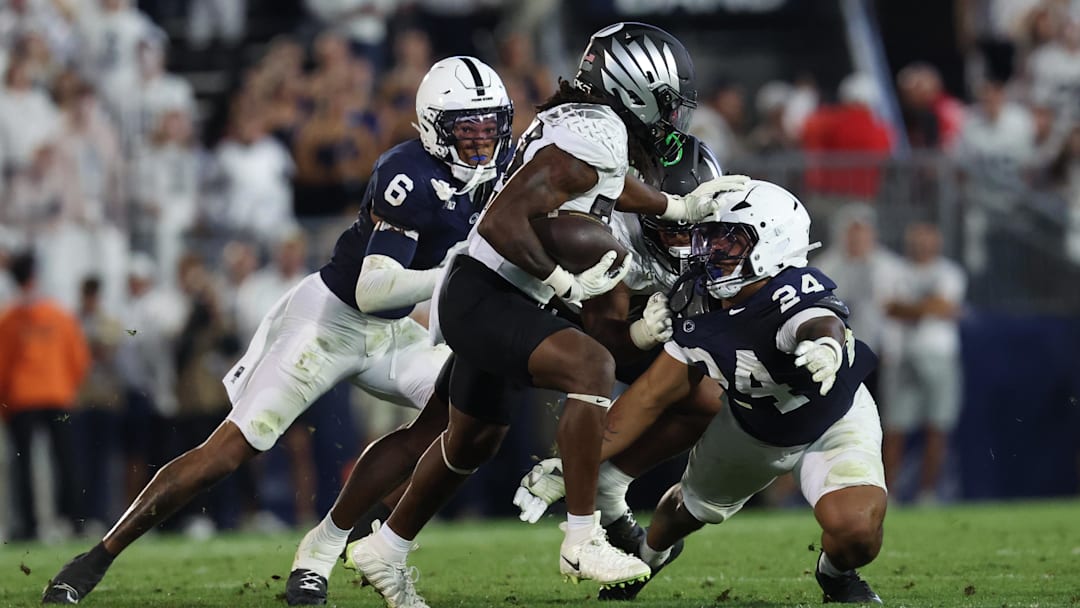 Sep 27, 2025; University Park, Pennsylvania, USA; Oregon Ducks running back Dierre Hill Jr. (23) runs for a gain past Penn State Nittany Lions linebacker Amare Campbell (24) during the second quarter at Beaver Stadium. Mandatory Credit: Matthew O'Haren-Imagn Images