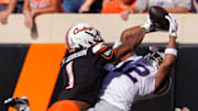 Nov 15, 2025; Stillwater, Oklahoma, USA; Kansas State Wildcats wide receiver Jaron Tibbs (12) attempts a reception around Oklahoma State Cowboys cornerback Jk Johnson (1) during the first half at Boone Pickens Stadium. Mandatory Credit: William Purnell-Imagn Images