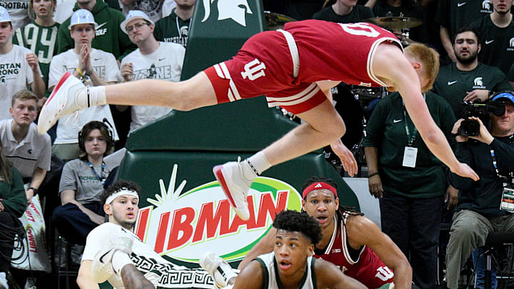 Feb 11, 2025; East Lansing, Michigan, USA;  Michigan State Spartans guard Jeremy Fears Jr. (1) scrambles for a loose ball during the second half as Indiana Hoosiers forward Luke Goode (10) flies-by overhead at Jack Breslin Student Events Center. Mandatory Credit: Dale Young-Imagn Images