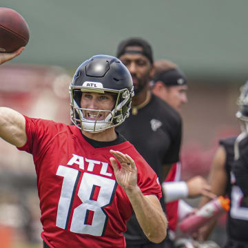 Atlanta Falcons quarterback Kirk Cousins throws a pass while coaches T.J. Yates and D.J. Williams watch from behind.