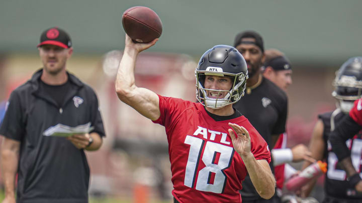Atlanta Falcons quarterback Kirk Cousins throws a pass while coaches T.J. Yates and D.J. Williams watch from behind.