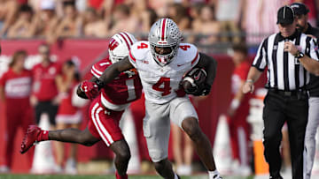 Oct 18, 2025; Madison, Wisconsin, USA;  Ohio State Buckeyes wide receiver Jeremiah Smith (4) runs against Wisconsin Badgers cornerback Geimere Latimer (1) in the second quarter at Camp Randall Stadium. Mandatory Credit: Jeff Hanisch-Imagn Images