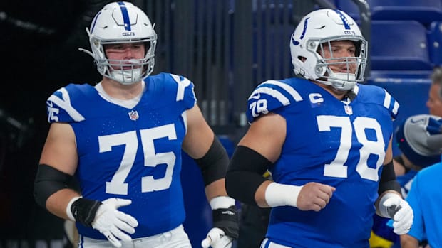 Colts linemen Will Fries and Ryan Kelly (blue jerseys) run out onto the field before the start of a game. 