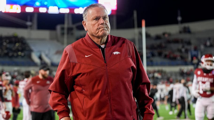 Arkansas head coach Sam Pittman walks down the sideline assisted by a cane