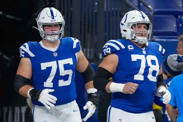 Indianapolis Colts guard Will Fries and center Ryan Kelly enter the field in blue jerseys.