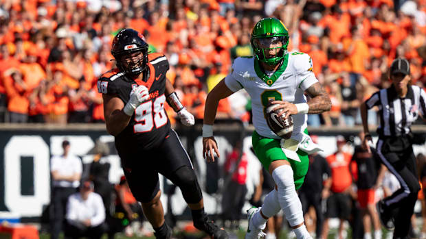 Oregon quarterback Dillon Gabriel breaks out under cover from Oregon State defensive lineman Thomas Collins as the Oregon Sta