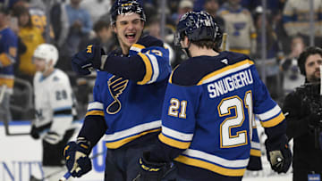 Apr 15, 2025; St. Louis, Missouri, USA; St. Louis Blues right wing Alexey Toropchenko (13) reacts with right wing Jimmy Snuggerud (21) after a win against the Utah Hockey Club at Enterprise Center to clinch a spot in the playoffs. Mandatory Credit: Jeff Le-Imagn Images