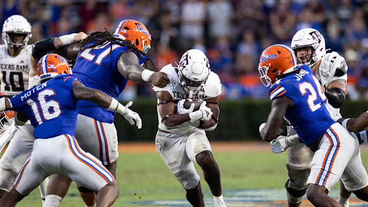 Sep 14, 2024; Gainesville, Florida, USA; Texas A&M Aggies running back EJ Smith (22) rushes with the ball past Florida Gators defensive lineman Desmond Watson (21), Florida Gators linebacker R.J. Moten (16) and Florida Gators defensive end Kamran James (24) during the second half at Ben Hill Griffin Stadium. Mandatory Credit: Matt Pendleton-Imagn Images