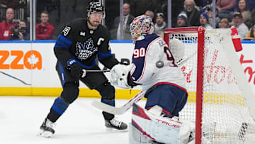 Jan 22, 2025; Toronto, Ontario, CAN; Toronto Maple Leafs center Auston Matthews (34) battles for the puck in front of Columbus Blue Jackets goaltender Elvis Merzlikins (90) during the first period at Scotiabank Arena. Mandatory Credit: Nick Turchiaro-Imagn Images