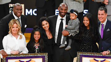Earvin "Magic" Johnson, Jeannie Buss, Gianna Bryant, Vanessa Bryant, Kobe Bryant holding Bianka Bryant, Natalia Bryant and Rob Pelinka pose for photos during a halftime ceremony retiring Kobe Bryant's two uniform numbers at Staples Center on Dec. 18, 2017.