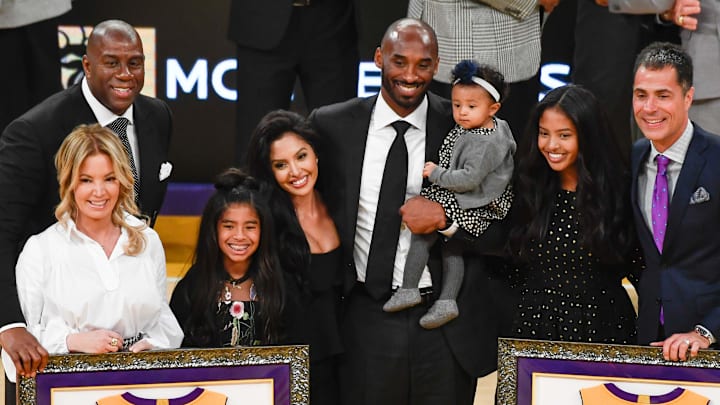 Earvin "Magic" Johnson, Jeannie Buss, Gianna Bryant, Vanessa Bryant, Kobe Bryant holding Bianka Bryant, Natalia Bryant and Rob Pelinka pose for photos during a halftime ceremony retiring Kobe Bryant's two uniform numbers at Staples Center on Dec. 18, 2017.