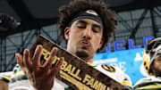 Green Bay Packers quarterback Jordan Love (10) celebrates with the Madden MVP trophy after defeating the Detroit Lions.