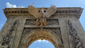 A phoenix and other magic creatures adorn the towering archway at Universal Epic Universe's Wizarding World of Harry Potter – Ministry of Magic.