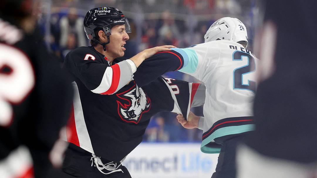 Mar 28, 2026; Buffalo, New York, USA;  Buffalo Sabres defenseman Logan Stanley (64) and Seattle Kraken defenseman Jamie Oleksiak (24) fight during the second period at KeyBank Center. Mandatory Credit: Timothy T. Ludwig-Imagn Images