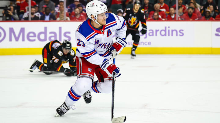 Nov 21, 2024; Calgary, Alberta, CAN; New York Rangers defenseman Adam Fox (23) skates with the puck against the Calgary Flames during the second period at Scotiabank Saddledome. Mandatory Credit: Sergei Belski-Imagn Images
