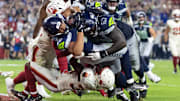 Sep 25, 2025; Glendale, Arizona, USA; Seattle Seahawks running back Zach Charbonnet (26) is pushed across the goal line by tackle Charles Cross (67) to score a touchdown against Arizona Cardinals safety Jalen Thompson (34) in the second quarter at State Farm Stadium. Mandatory Credit: Mark J. Rebilas-Imagn Images