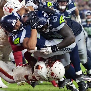 Sep 25, 2025; Glendale, Arizona, USA; Seattle Seahawks running back Zach Charbonnet (26) is pushed across the goal line by tackle Charles Cross (67) to score a touchdown against Arizona Cardinals safety Jalen Thompson (34) in the second quarter at State Farm Stadium. Mandatory Credit: Mark J. Rebilas-Imagn Images