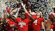 The Georgia Bulldogs celebrate with the trophy after defeating the Texas Longhorns in overtime in the 2024 SEC Championship game at Mercedes-Benz Stadium.