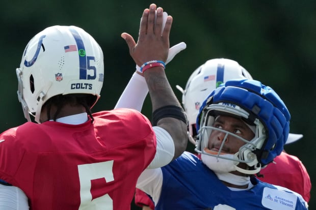 Football players Anthony Richardson and Josh Downs high five after a play in practice.