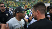 Colorado coach Deion Sanders, left, and Oregon's Dan Lanning meet at midfield after their game in Eugene