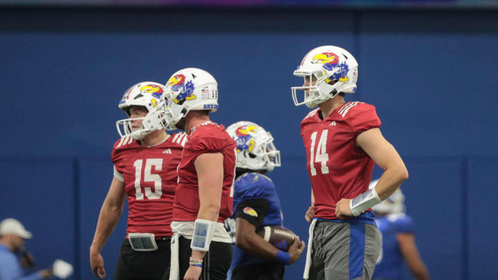 Kansas quarterbacks, from left, redshirt freshman Cole Ballard (15) redshirt junior Ben Easters (16) and redshirt sophomore Mikey Pauley (14) await instructions during a team practice Tuesday, April 2, 2024, inside the Indoor Football Practice Facility.