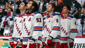 Oct 9, 2024; Pittsburgh, Pennsylvania, USA;   New York Rangers players left wing Chris Kreider (left) and center Mika Zibanejad (93) defensemen Jacob Trouba (8) and Braden Schneider (4) watch a video tribute to the late Columbus Blue Jackets left wing Johnny Gaudreau (not pictured) before the game against the Pittsburgh Penguins at PPG Paints Arena. Mandatory Credit: Charles LeClaire-Imagn Images