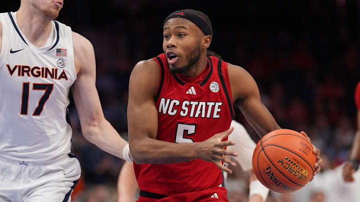 Mar 12, 2026; Charlotte, NC, USA; Virginia Cavaliers center Johann Gr¸nloh (17) defends against NC State Wolfpack guard Tre Holloman (5) during the second half at Spectrum Center. Mandatory Credit: Jim Dedmon-Imagn Images