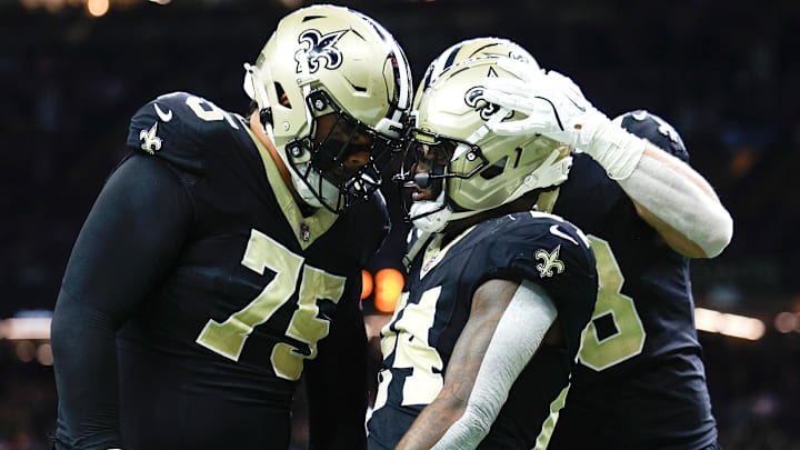 New Orleans Saints RB Devin Neal (24) celebrates with RT Tailese Fuaga (75) and TE Jack Stoll (88) after scoring a touchdown against the Carolina Panthers on Dec. 14, 2025.