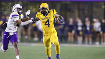 Sep 7, 2024; Morgantown, West Virginia, USA; West Virginia Mountaineers running back CJ Donaldson Jr. (4) runs the ball and stiff arms Albany Great Danes defensive back Daiyaan Hawkins (4) during the fourth quarter at Mountaineer Field at Milan Puskar Stadium. Mandatory Credit: Ben Queen-Imagn Images