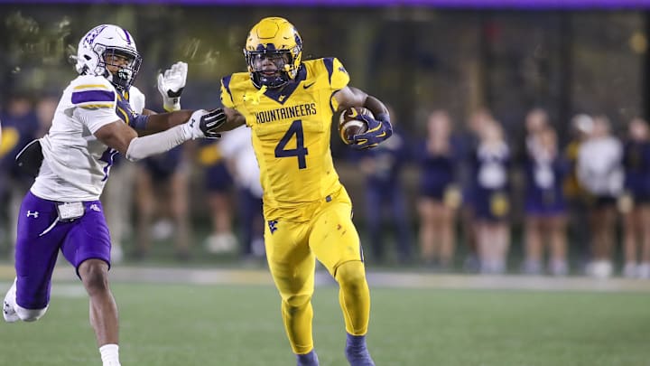 Sep 7, 2024; Morgantown, West Virginia, USA; West Virginia Mountaineers running back CJ Donaldson Jr. (4) runs the ball and stiff arms Albany Great Danes defensive back Daiyaan Hawkins (4) during the fourth quarter at Mountaineer Field at Milan Puskar Stadium. Mandatory Credit: Ben Queen-Imagn Images