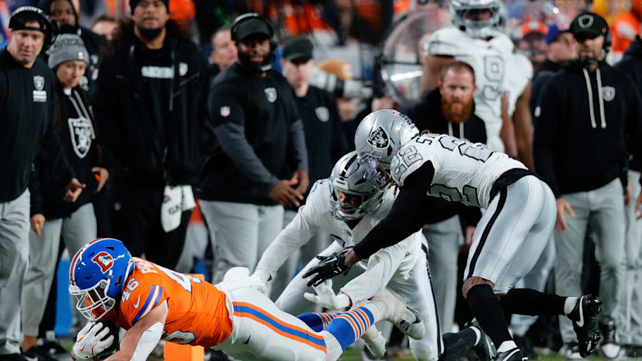 Raiders defenders lunge toward a diving Broncos player