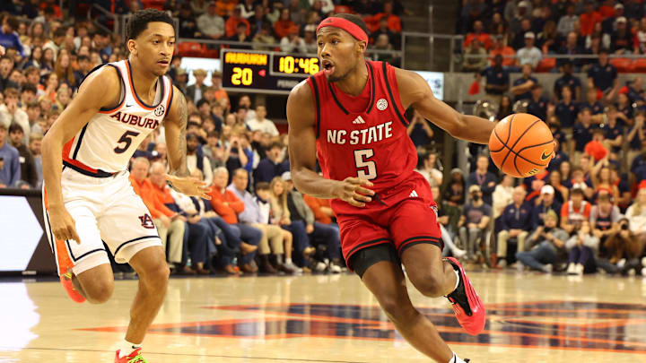 Dec 3, 2025; Auburn, Alabama, USA;  NC State Wolfpack guard Tre Holloman (5) runs a play as Auburn Tigers guard Kaden Magwood (5) defends during the first half at Neville Arena. Mandatory Credit: John Reed-Imagn Images
