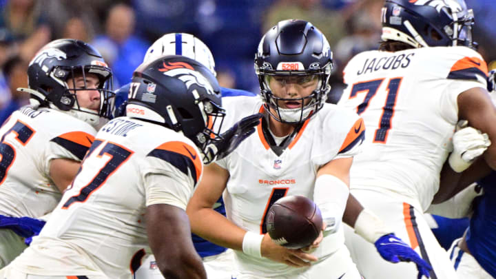 Aug 11, 2024; Indianapolis, Indiana, USA;  Denver Broncos quarterback Zach Wilson (4) hands the ball off to Denver Broncos running back Audric Estime (37) during the second half at Lucas Oil Stadium.