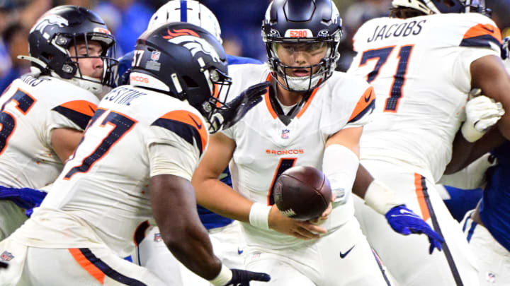 Denver Broncos quarterback Zach Wilson (4) hands the ball off to Denver Broncos running back Audric Estime (37) during the second half at Lucas Oil Stadium.