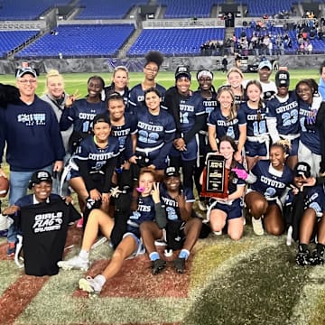 The Baltimore Ravens mascot joins the players and coaches of the Clarksburg girls flag football team, on the turf of M&T Bank Stadium, after the Coyotes won the Maryland state girls flag football championship on Friday.