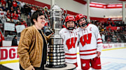 Wisconsin Badgers forward Casey O'Brien (26, center) and defender Caroline Harvey (4) accept the WCHA regular season trophy from commissioner Michelle McAteer after in a game against the Minnesota Gophers on Saturday, February 8, 2025, at LaBahn Arena in Madison, Wisconsin. Wisconsin won, 8-2.