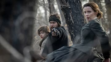 AMERICAN PRIMEVAL. (L to R) Preston Mota as Devin Rowell, Taylor Kitsch as Isaac, and Betty Gilpin as Sara Rowell in Episode 101 of American Primeval. Cr. Matt Kennedy/NETFLIX © 2023