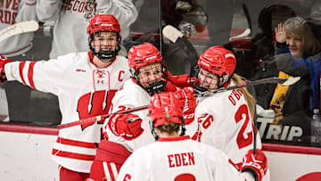 Teammates mob Wisconsin Badgers left wing Kirsten Simms (27) after her goal against the Minnesota Gophers in the second period of a game Sunday, February 9, 2025, at LaBahn Arena in Madison, Wisconsin.