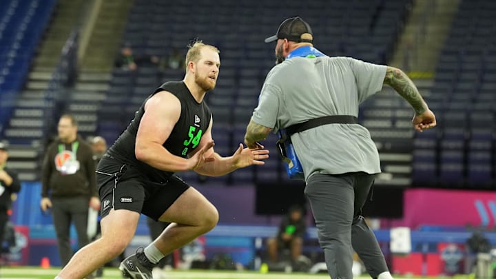 Mar 1, 2026; Indianapolis, IN, USA; Washington offensive lineman Carver Willis (OL54) interacts with the Los Angeles Chargers assistant offensive line coach Nick Hardwick during the NFL Scouting Combine at Lucas Oil Stadium. Mandatory Credit: Kirby Lee-Imagn Images