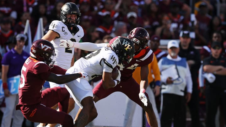 Oct 14, 2023; Blacksburg, Virginia, USA; Wake Forest Demon Deacons wide receiver Ke'Shawn Williams (13) is tackled by Virginia Tech Hokies safety Jaylen Jones (15) and cornerback Dorian Strong (44) during the first quarter at Lane Stadium. Mandatory Credit: Peter Casey-USA TODAY Sports