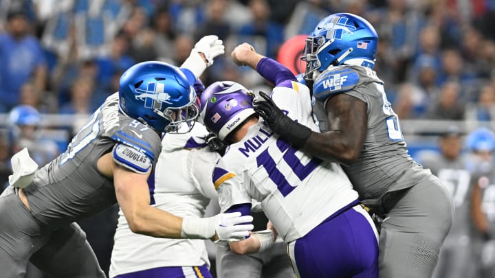 Minnesota Vikings quarterback Nick Mullens (12) gets hit by Detroit Lions defensive ends Aidan Hutchinson (97) and Josh Paschal (93).