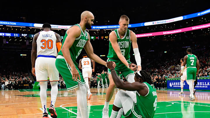 Dec 8, 2023; Boston, Massachusetts, USA;  Boston Celtics guard Jrue Holiday (4) is helped to his feet by guard Derrick White (9)  and center Kristaps Porzingis (8) during the first half against the New York Knicks at TD Garden. Mandatory Credit: Eric Canha-Imagn Images