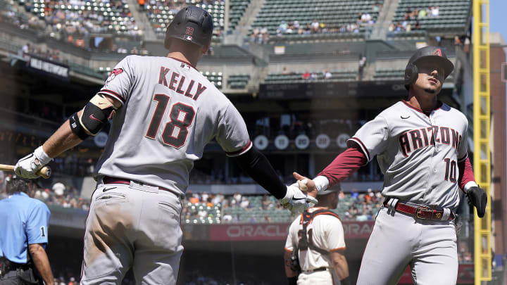 Josh Rojas slapping hands with Carson Kelly after scoring for the Arizona Diamondbacks