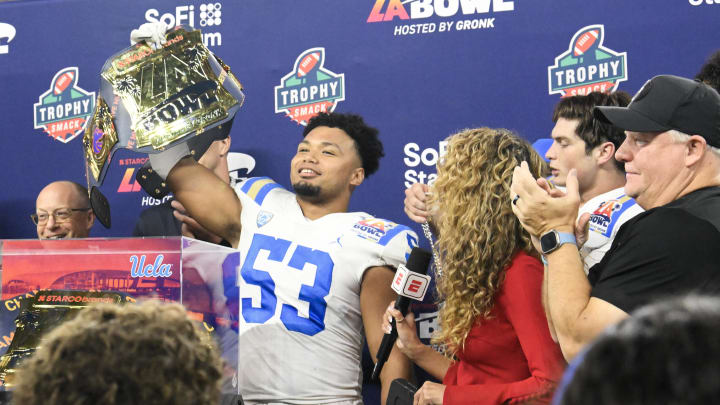Dec 16, 2023; Inglewood, CA, USA; UCLA Bruins linebacker Darius Muasau (53) holds up the award for defensive player of the game after defeating the Boise State Broncos in the Starco Brands LA Bowl at SoFi Stadium. At right is UCLA head coach Chip Kelly.  