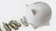 White piggy bank eating USA dollars one at a time, financial...