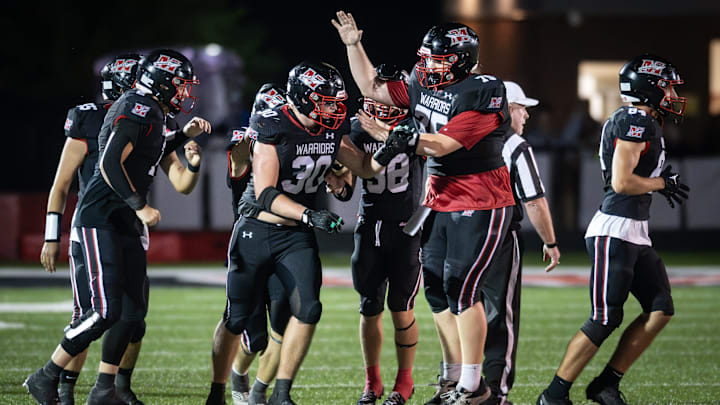 Muskego teammates mob defensive lineman Caleb Hein (30) after his interception in the final minute sealed a 21-17 victory over Arrowhead in a game Friday, September 19, 2025, at Muskego High School in Muskego, Wisconsin.