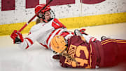 Wisconsin Badgers center Casey O'Brien (26) slides into the boards after being tripped on a breakaway by Minnesota Gophers defender Sydney Morrow (32) in the second period of a game Sunday, February 9, 2025, at LaBahn Arena in Madison, Wisconsin.