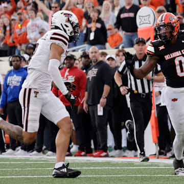 Oklahoma State's Ollie Gordon II runs the ball against Texas Tech's C.J. Baskerville during an NCAA football game on Saturday, Nov. 23, 2024, in Stillwater, Okla.